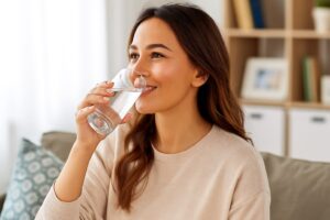 Consejo de belleza: mujer hidratándose con agua en ambiente hogareño

